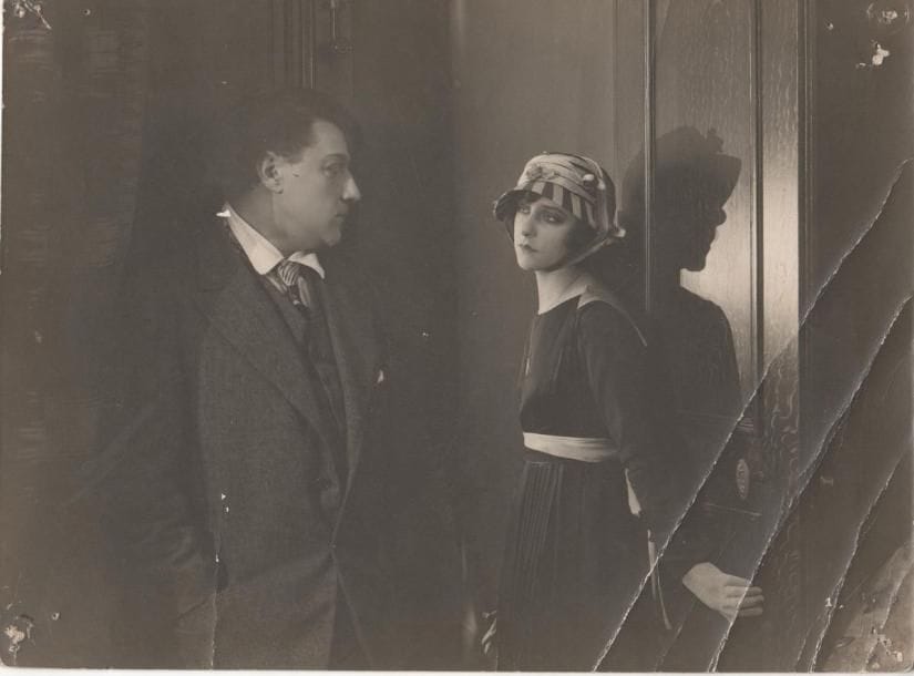 [Sacha GUITRY et Yvonne PRINTEMPS]
Photographie du film Un roman d'amour et d'aventure, [fin 1917]. Tirage argentique d'époque, 16,5x22,5cm (plis, trous de punaises aux coins); cachet encre G. Troussier au dos. TRèS RARE PHOTOGRAPHIE DU PREMIER FILM JOUé PAR SACHA GUITRY, Un roman d'amour et d'aventure, réalisé par René Hervil et Louis Mercanton fin 1917 sur un scénario de Sacha Guitry, qui y joue un double rôle de jumeaux qui annonce La Vie d'un honnête homme. Ce sera le seul film muet de Guitry, qui est ici face à Yvonne Printemps. On joint  4 tirages modernes d'images du film