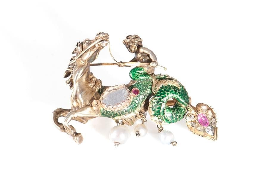 Broche en vermeil, sculptée en ronde bosse d'un hippocampe, le flanc appliqué d'un diamant table, chevauché par Triton, la queue émaillée terminée par un rubis entouré de roses, agrémentée de trois perles en pampilles. époque XIXe siècle. Poids brut: 23,5 g (manque)