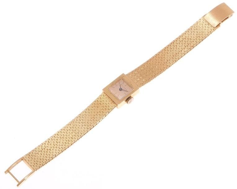 Montre de dame en or jaune, cadran carré, fond satiné, index bâtons, bracelet ruban souple d'or jaune, mouvement mécanique. Poids brut: 41,9 g (remontoir métal)