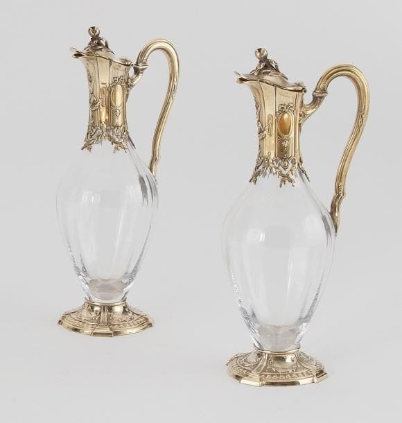 Paire d'aiguières cristal et vermeil, le piédouche, le col et l'anse à décor Louis XVI, alternant rubans, médaillons et feuillage en chute. Poinçon minerve, dernier quart du XXe siècle. Orfèvre: TETARD Frères. Haut.: 32 cm Ce lot pourra être joint au lot précédent qui est son pendant en argent