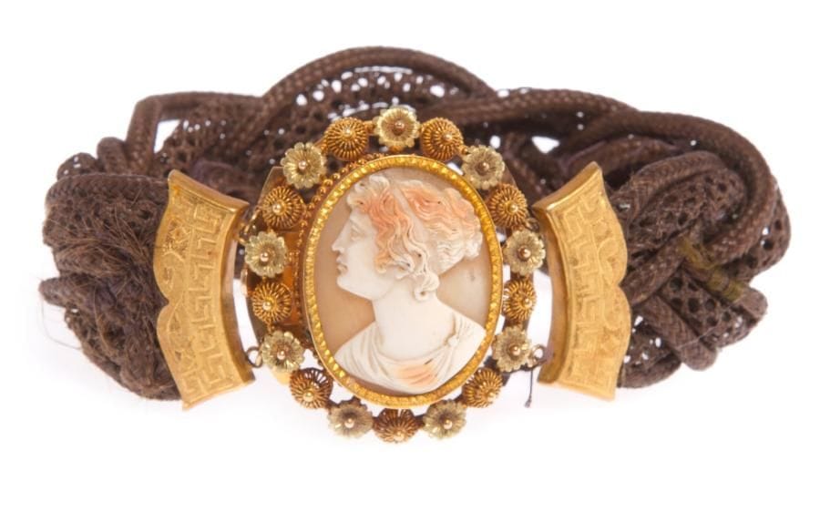 Bracelet en cheveux tressés, fermoir en or jaune et rose orné d'un camée coquille ciselé d'une jeune femme en buste. Première moitié du XIXe siècle. Poids brut: 19,5 g (manques)
