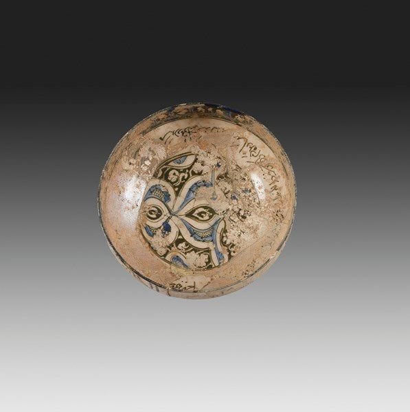 Coupe aux demi-palmettes, Syrie, deuxième moitié du XIIIe siècle Coupe hémisphérique sur piédouche en céramique siliceuse, à décor peint en cobalt et noir sous glaçure transparente sur fond crème. Composition de demi-palmettes dans un médaillon central, bordé par une frise calligraphiée naskhî. Au rebord, frise pseudo-coufique en réserve sur fond noir et rehauts bleus. Au revers, frise épigraphique naskhî et rinceaux foliés. D.: 20 cm; H.: 17 cm État: irisations, fractures recollées et un petit manque au rebord.


A cobalt glazed pottery bowl, Syria, second half of the 13th century