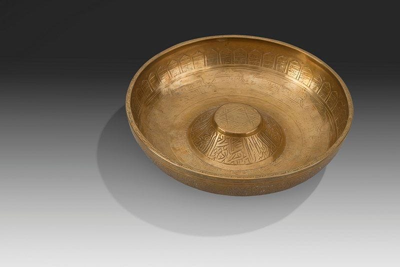 Coupelle prophylactique, Jezireh, XVIe - XVIIIe siècle Coupelle à ombilic en laiton, gravée à l?intérieur de cartouches entrelacés et arcatures meublés de pseudo-inscriptions autour d?une étoile à six branches, et à l?extérieur d?un large bandeau pseudo-épigraphié autour d?une rosette centrale. D.: 18,5 cm État: forte érosion des inscriptions. Provenance: ancienne collection Toulouse-Lautrec, vente publique, Paris, Me F. de Ricqlès, exp. Cabinet Soustiel-David, Paris, 25 septembre 1998, lot 8.; collection J. M. G., Paris. L?usage de ces coupelles prophylactiques était très répandu dans le monde musulman, jusqu?à une période relativement récente. Il est parfois difficile de leur attribuer une datation précise, tant l?usage en a érodé les motifs. Pour d?autres coupelles du même type voir le catalogue de l?exposition À l?ombre d?Avicenne. La médecine au temps des califes, Paris, IMA, 18 nov. 1996 au 2 mars 1997, p. 226-227. 



A prophylactic brass cup, Jezireh, 16th - 18th century