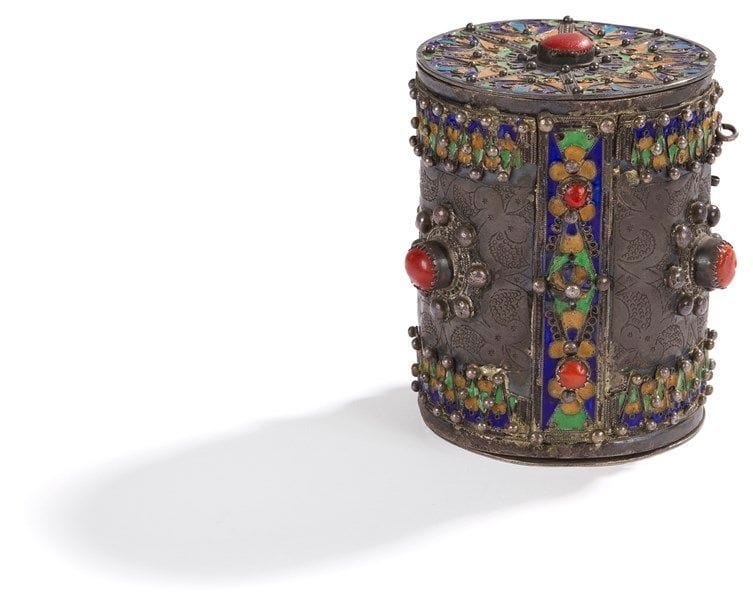 Bracelet de cheville monté en boite, akhelkhâl, Algérie, Grande Kabylie, Benni Yenni, XXe siècle Argent ciselé, rehaussé d?émail bleu, jaune, vert et de cabochons de corail, remonté en boite. Avec le fond et le couvercle rapportés. Le couvercle reprend le même décor émaillé. H.: 11 cm; PB: 434 g Les artisans, à la fin du XIXe siècle, ont imaginé de transformer les chevillières et les bracelets en boîtes à cigares ou en vide-poches. Voir: H. Camps-Fabrer, Bijoux berbères d?Algérie, p. 116-117. 


A silver anklet mounted as a box, Algeria, Great Kabylia, Benni Yenni, 20th century