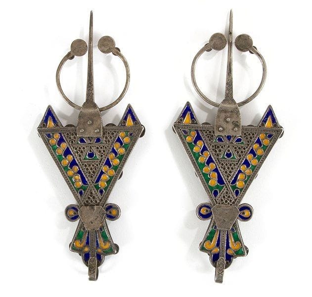 Paire de fibules, abzim, Algérie, Grande Kabylie, Benni Yenni, XXe siècle Fibule de forme triangulaire en argent ciselé, décorée d?émaux cloisonnés jaune, vert et bleu, rehaussée de trois grands cabochons de corail. Le revers est également émaillé des mêmes couleurs. Dim.: 21 x 8,5 cm; P.: 280 g
 


A pair of enamelled silver fibulae, Algeria, Great Kabilya, Benni Yenni, 20th century