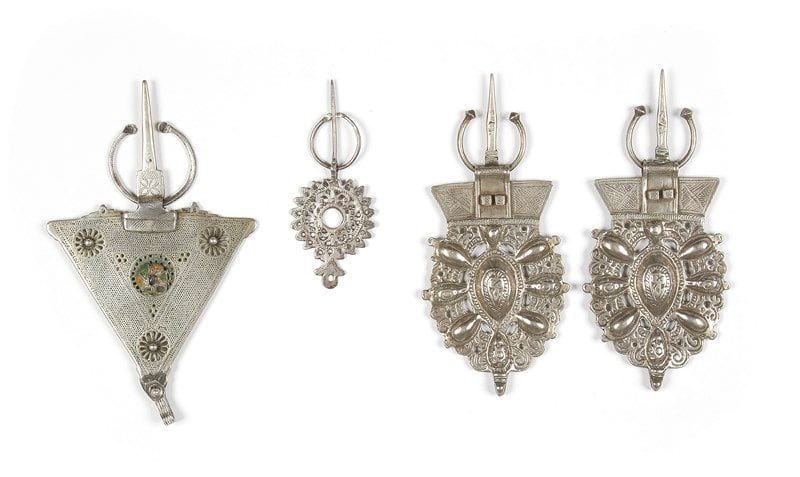 Quatre fibules en argent, Maroc, XXe siècle Paire de très grosses fibules en argent moulées en mandorle rayonnante, région de Nador; une fibule tiezerzaï dite «de ver» à poinçons, cabochons et applique verte et orange, restauration au niveau de la «pique»; la dernière, de petite taille, ajourée en forme de soleil. PB.: 319 g; 155 g; 27 g 



Four silver fibulae, Morocco, 20th century