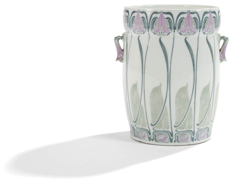Georges de FEURE (1868-1943) pour L’ART NOUVEAU BING

Rare vase à oreilles formant seau, les anses détachées traitées en clochette végétales.
Épreuve en porcelaine émaillée blanc au décor gravé et polychromé, parme, pistache et vert, de motifs végétaux et géométriques traités dans le goût symboliste.
Circa 1902.
Une infime gerce sur la tranche de la bordure du col.
Manufacture Gérard, Dufraissex et Abbot.
Marqué des cachets monogrammes, GDF et ANB, et porte la marque Leuconoé sous la base.
Hauteur : 20 cm
Exposition :
« Salon annuel de La Société Nationale des Beaux-Arts, Paris, 1902 » Un modèle identique fut présenté lors de cette manifestation.
Musée :
Un modèle identique est conservé au Musée Adrien Dubouché à Limoges et un autre au Musée des Arts Décoratifs à Paris.
Bibliographie :
« Art et Décoration » 1er semestre 1902. Modèle identique reproduit page 26. 
« Deutsche Kunst und Dekoration » Band XII, avril-septembre 1903. Modèle identique, assorti d’anses en métal, reproduit page 319 dans un article entièrement consacré à l’artiste.
« The Paris Salons 1895-1914, volume IV : Ceramics & Glass » par Alastair Duncan, Antique Collectors’ Club, 1998. Modèle du vase reproduit page 162.
« Der Modern Stil, The Modern Style, Jugendstil, Art Nouveau, 1899-1905 » Julius Hoffmann Jr., Éditions Arnoldsche, Germany, 2006. Modèle identique reproduit page 321.