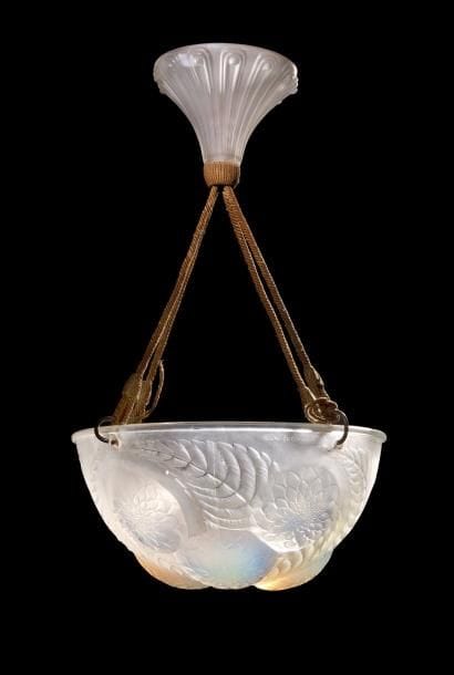 René LALIQUE (1860-1945)
Dahlias, modèle créé en 1921, supprimé du catalogue en 1932
Plafonnier complet de son cache-bélière.
Coupe en verre opalescent moulé pressé et, en partie, satiné.
Cache-bélière en verre blanc moulé pressé.
Suspentes électrifiées en passementerie.
Signé R. LALIQUE France, en intaille sur le pourtour de la vasque.
Diamètre : 30 cm
Bibliographie :
«R. Lalique, catalogue raisonné de  l’œuvre de verre » Félix Marcilhac, Les Éditions de l’Amateur, Paris, 2004. Modèle identique reproduit page 671 et inscrit sous la référence 2459.