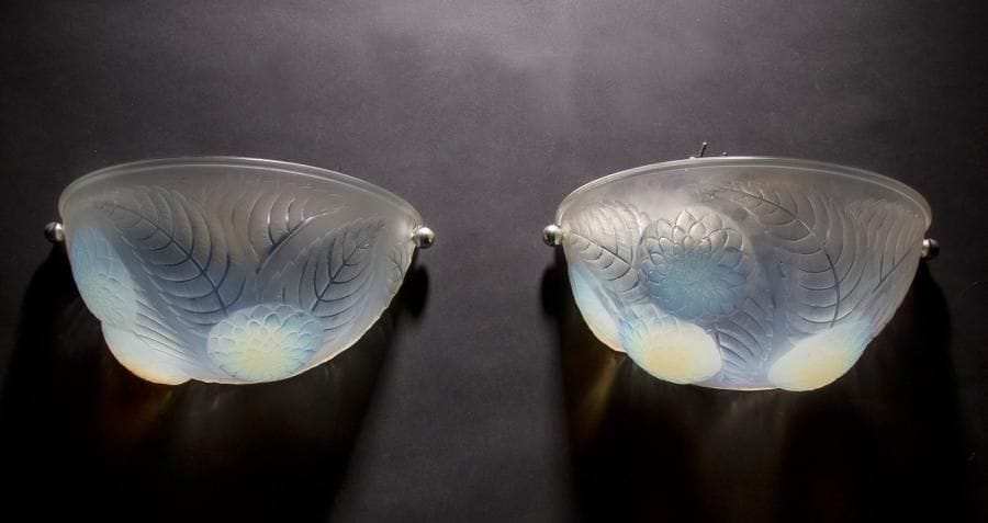 René LALIQUE (1860-1945)
Dahlias, modèle créé en 1921, supprimé du catalogue en 1932
Paire d’appliques en demi-lune.
Épreuves en verre opalescent moulé pressé et, en partie, satiné.
Montures métalliques non d’origine.
Signé R. LALIQUE France, en intaille sur l’une des appliques.
Largeur : 30 cm
Bibliographie :
«R. Lalique, catalogue raisonné de l’œuvre de verre » Félix Marcilhac, Les Éditions de l’Amateur, Paris, 2004. Modèle identique reproduit page 592 et inscrit sous la référence 2011.