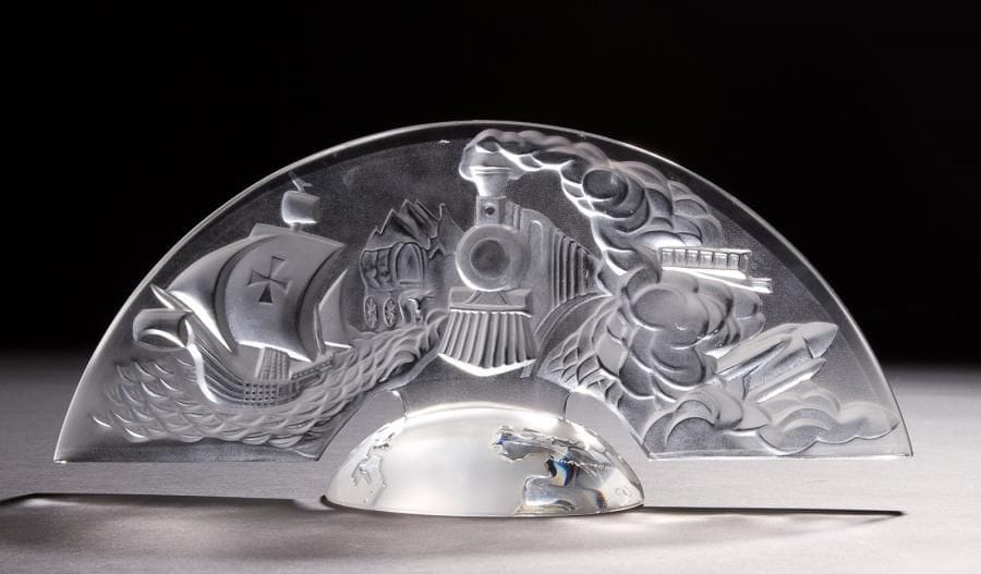Maison LALIQUE
America, 1992
Motif décoratif en cristal moulé pressé et, en partie, satiné.
Un infime éclat vers la mortaise de la base.
Signé LALIQUE ® France sur la tranche de la partie supérieure, marqué 500ème anniversaire de la Découverte de l’Amérique par Christophe Colomb 1492-1992 et signé à la pointe M LALIQUE en lettres cursives, façon signature olographe, sous la base.
16,5 x 36 x 13 cm