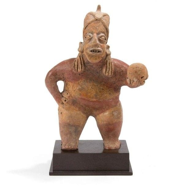 Joueur de pelote. Prêt à l?action, il tient la balle dans sa main gauche. Il est vêtu d?une culotte courte et paré de longues boucles d?oreilles. Sa tête est ceinte d?un casque à crête avec lanières retenues par un médaillon central. Ce jeu rituel répandu dans toute la Méso-Amérique symbolisait le parcours du soleil représenté par la balle en caoutchouc. Terre cuite brune à engobe rouge et crème. Traces d?oxyde de manganèse. Culture Jalisco, Mexique 100 av. - 250 ap. J.-C. H: 23 cm - l: 17 cm - Ep: 8,5 cm Provenance: Galerie «Le futur Antérieur», Saint-Ouen