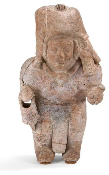 Femme debout richement parée. Elle est vêtue d?un long pagne tandis que sa poitrine est laissée nue. Un collier avec médaillon orne son cou. Une haute coiffe enserre sa tête. Elle est agrémentée sur le côté gauche d?une boucle qui retombe sur l?épaule. Elle tient dans sa main gauche un bâton cérémoniel. Un récipient avec anse repose sur le poignet droit. Terre cuite brune avec trace de brûlures et oxydes de manganèse. Culture Jama, Coaque, Équateur 500 av. - 500 ap. J.-C. H: 33,5 cm - l: 18 cm - Ep: 12,5 cm État: Cassé et recollé. Provenance: Collection Privée, France