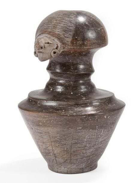 Vase à goulot orné d?un visage humain. Terre cuite brune à engobe noir lustré. Culture Mantena, Équateur 500 av. - 500 ap. J.-C. H: 21 cm - l: 14 cm - Ep: 15 cm État: Cassé et recollé (cou). Provenance: Collection privée, France