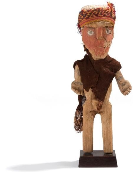 Homme debout vêtu d?un poncho et d?une coiffe en bandeau. Les bras sont articulés. Le visage à l?expression souriante et recouvert de cinabre. Les yeux sont peints en blanc et les pupilles noires sont faites de goudron. Corps en bois recouvert de cinabre, peinture blanche et goudron. Habit et coiffe en tissu. Culture Chancay, Pérou 1100 - 1400 ap. J.-C. H: 45 cm - l: 16 cm - Ep: 9 cm État: Cassé et recollé au niveau du bras gauche. Provenance: Ancienne collection danoise depuis 1970