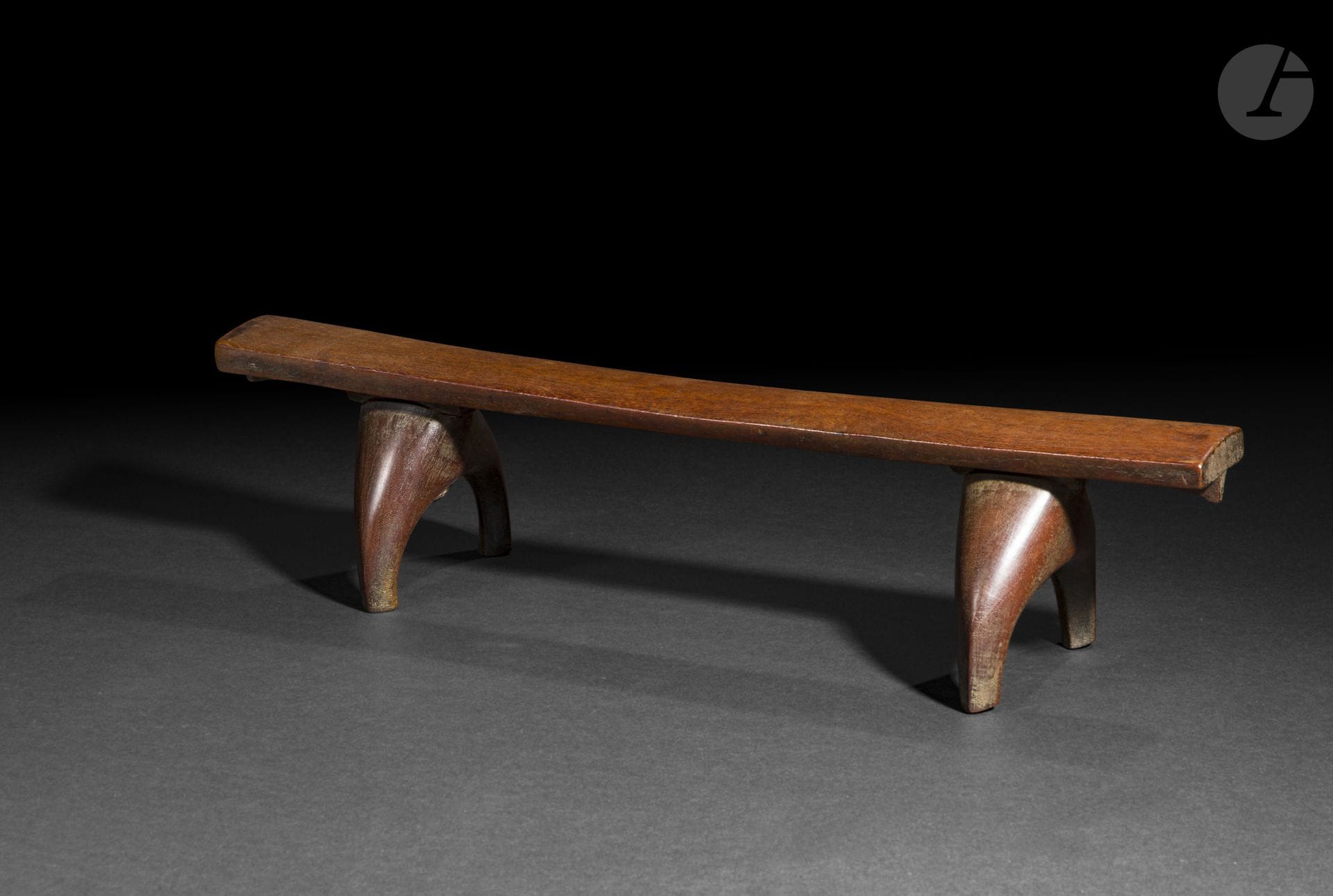 Appui-nuque kali toloni, archipel des îles Tonga
Longueur : 49,8 cm
Bois et fibres végétales.
Caractéristique des productions de l’archipel des Tonga, le kali toloni était utilisé pour soutenir la nuque durant le sommeil tout en préservant les coiffures élaborées. La pureté de ses lignes, l’équilibre de sa construction et la qualité de son exécution témoignent du raffinement des arts domestiques tongiens, où les objets du quotidien allient avec harmonie fonctionnalité et élégance.

Provenance :
- Hurst Gallery.
- Christie’s, Paris, 10 juin 2008, n° 169.
