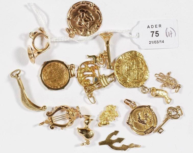 Lot de pendentifs et charms en or jaune: une trompette, une pièce de 10 Francs or, un Snoopy, une pièce espagnole, une lyre, un cor, une médaille signée Becker, une médaille angelot, une pelotte basque, une pépite, une clé, un singe savant, un cornet à pistons, un buste de Nefertiti, un trident, un dauphin, une main de Fatma. Poids brut total: 29,2 g