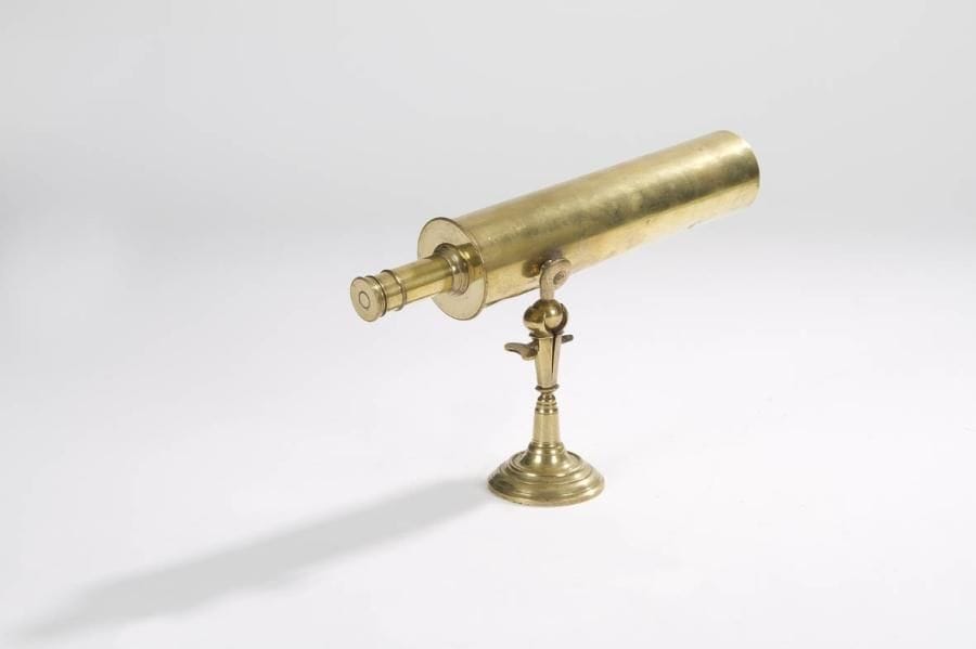 Rare petit télescope de salon ou d'alcôve en laiton poli, à miroirs. Monté sur rotule d'articulation et reposant sur un pied tourné en laiton. C. 1760. Complet de ses deux miroirs. Manque le cache avant de protection. Longueur: 24,5 cm