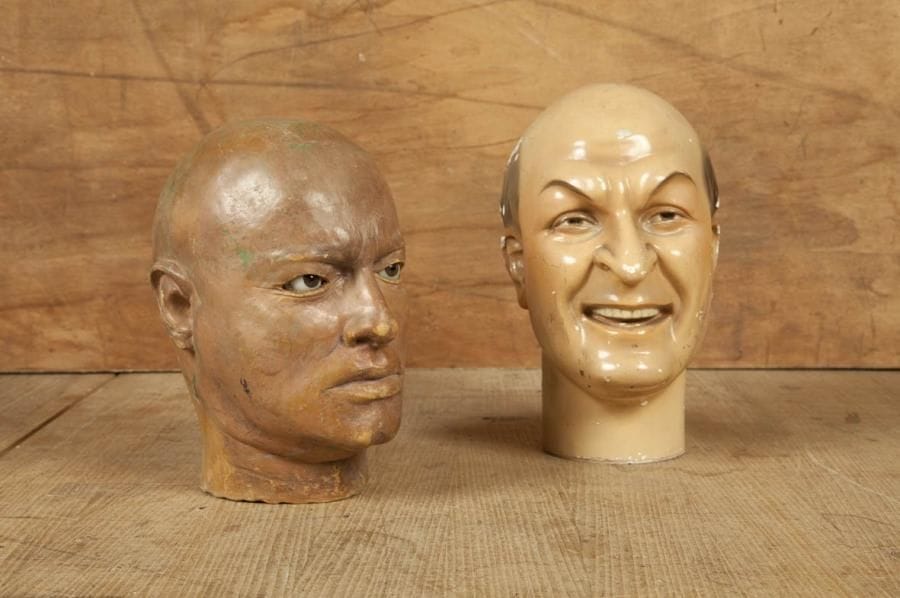Deux têtes masculines. L'une en plâtre et peinture vernissée, l'autre en matière synthétique (latex?) aux yeux de verre. C. 1940. Hauteur: 28 et 30 cm
