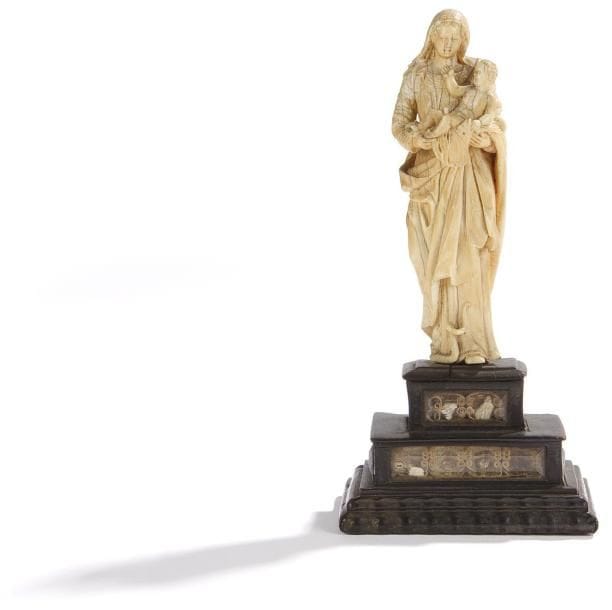 Vierge à l'Enfant en ivoire sculpté en ronde-bosse, foulant le serpent, sur un socle reliquaire en ébène à deux étages avec verres biseautés. XVIIe siècle Hauteur: 18 cm (Légers accidents sur les pieds)