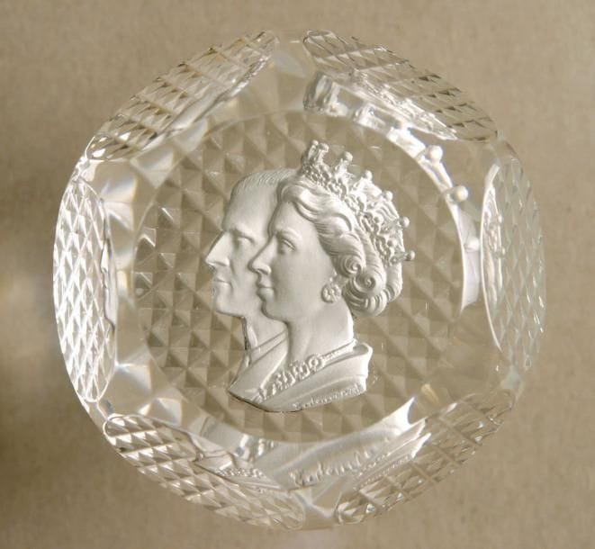 BACCARAT
Presse-papiers orné d'un cristallo-cérame, par G. Poillerat, représentant les profils gauches de la reine Elizabeth II et le duc d'Edinburgh; taille à six pontils, fenêtre supérieure et pointes de diamants au revers. Produit pour le couronnement de la reine en 1953. Diam. 6,8 cm - Haut. 3,4 cm