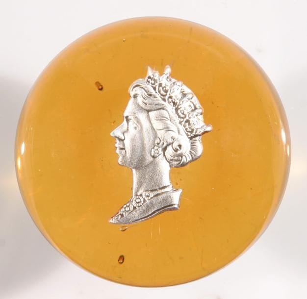 SAINT-LOUIS
Presse-papiers à fond ambre orné d'un cristallo-cérame, par G. Poillerat, représentant le profil gauche de la reine Elizabeth II. Diam. Produit pour le couronnement de la reine en 1953. Diam. 7,4 cm - Haut. 4,6 cm
