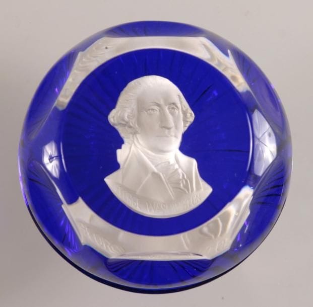 Cristal d'Albret (Vianne)
Presse-papiers à fond bleu orné d'un cristallo-cérame représentant le buste de George Washington. Taille à six pontils, fenêtre supérieure et motif rayonnant au revers. Diam. 7,5 cm - Haut. 4,5 cm