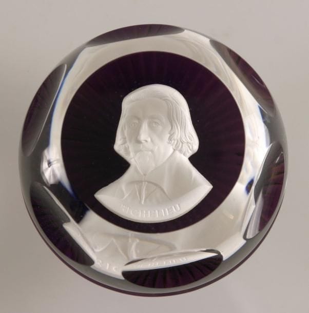 BACCARAT
Presse-papiers à fond violet orné d'un cristallo-cérame représentant le buste du cardinal de Richelieu. Taille à six pontils, fenêtre supérieure et motif rayonnant au revers. Produit en 1977. Diam. 7,4 cm - Haut. 4,6 cm