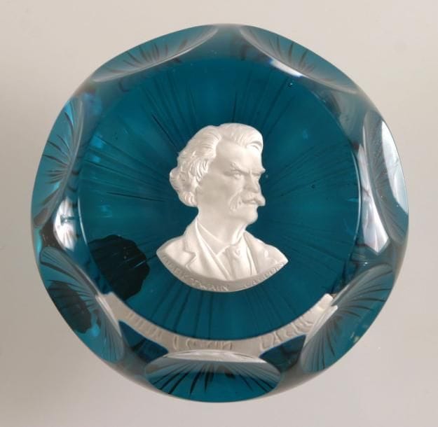 Cristal d'Albret
Presse-papiers à fond vert translucide orné d'un cristallo-cérame représentant le buste de l'écrivain américain Marc Twain. Taille à six pontils, fenêtre supérieure et motif rayonnant au revers. Produit en 1969. Diam. 7,3 cm - Haut. 4 cm