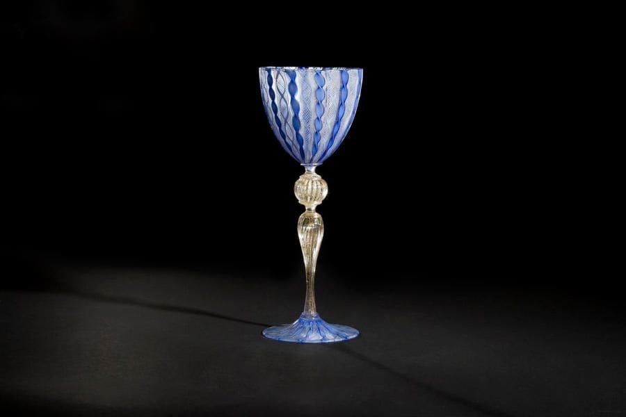 MURANO
Verre à pied en verre à décor de torsades rubanées et filigranées bleu de lin et aventurine; jambe côtelée à saupoudrage doré. Haut. 20,5 cm