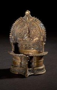 Lampe à huile. Inde Méridionale - Tamil Nadu. XVIIIe / XIXe siècle. Bronze Lampe à huile consistant en une gorge circulaire montée sur un haut pied étagé. Elle est munie d'un réflecteur orné d'un décor de Gajalakshmi représentant la déesse Lakshmi tenant un lotus dans chaque main et ointe d'eau lustrale par deux éléphants. Hauteur: 14 cm