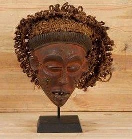 TSHOKWE (Angola) Masque. Masque "Pwo" au visage réaliste en bois rehaussé d'ocre rouge, coiffe de tresses végétales, larges orbites et yeux en amandes, belle scarifications des joues et du menton, croix "cingelyengelye", signé de l'ordre du Christ du Portugal, sur le front. Hauteur: 23 cm Provenance: coll. Michel Gaud, Saint-Tropez