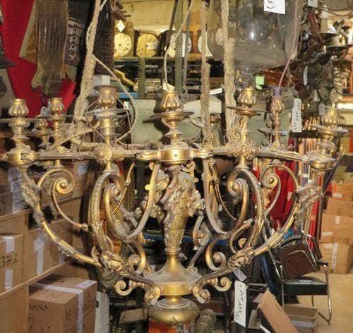 Lot de 5 lustres : 1 grand lustre à décor de volutes à 12 lumières et vase central orné d'une guirlande de fleurs en métal doré, 2 lustres en bois, 2 lustres en métal.