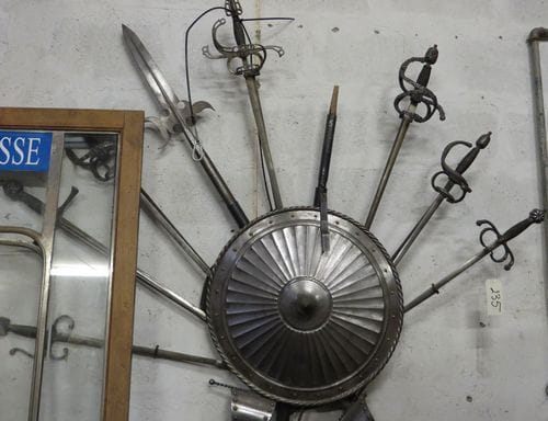 Trophée d'arme en métal et un trophée d'armes en bois en forme d'écusson.