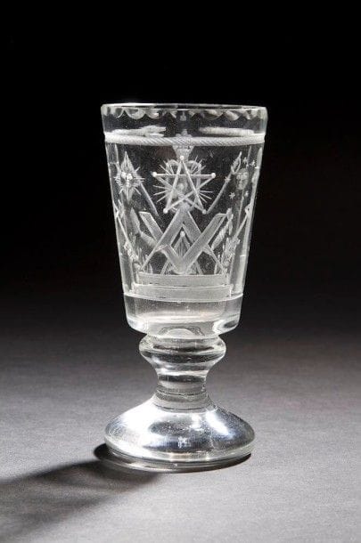 Verre sur pied gravé de nombreux symboles de la franc-maçonnerie : compas-équerre, étoile flamboyante, glaives, soleil-lune, etc. Début du XXe siècle. (haut. 13,5 cm).