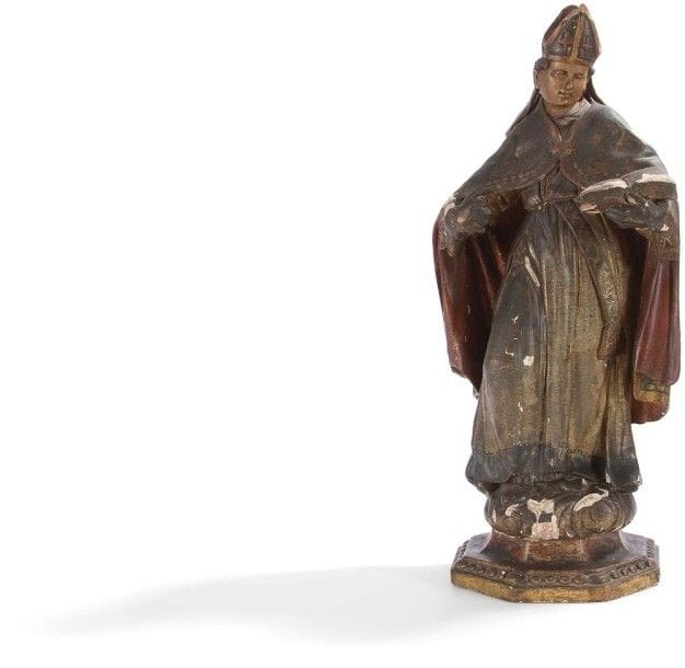 Saint évêque en bois de résineux sculpté en ronde-bosse, polychromé et doré. Debout, une jambe fléchie, il porte dans sa main gauche un livre ouvert ; tête imberbe ceinte d’une mitre à fanons ; il est vêtu d’une aube ceinturée et blousante, d’une étole et d’une chape retenue sur la poitrine ; mains gantées et manipule au poignet gauche. Base octogonale moulurée et ornée de grosses perles.
Espagne, XVIIe / XVIIIe siècle.
H. : 59,5 cm
(Accidents à la polychromie, manques aux mains).