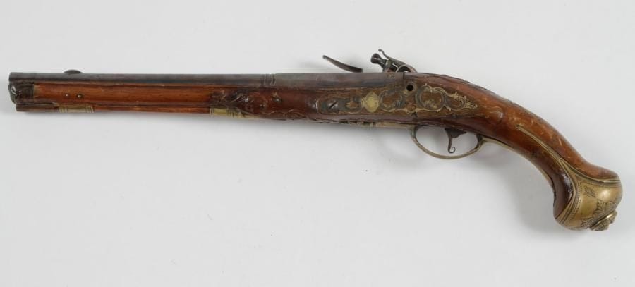Long pistolet d'arçon à silex.
Canon rond à pans au tonnerre, poinçonné au tonnerre «A.S» sous couronne, rebleui. Platine signée «A. STREIGNARD» et chien col de cygne (postérieur) à corps plat. Garnitures, contre-platine et pièce de pouce en laiton découpé et ciselé. Calotte à longues oreilles finement ciselée d'un masque grimaçant et des feuillages. Crosse et fût à embout en corne, en noyer sculpté. Baguette en bois à embout en corne.
A.B.E. Vers 1760- 1780. (Enture au fût)
STREIGNARD: Famille d'Arquebusiers liégeois, on retrouve un P. STREIGNARD vers 1820