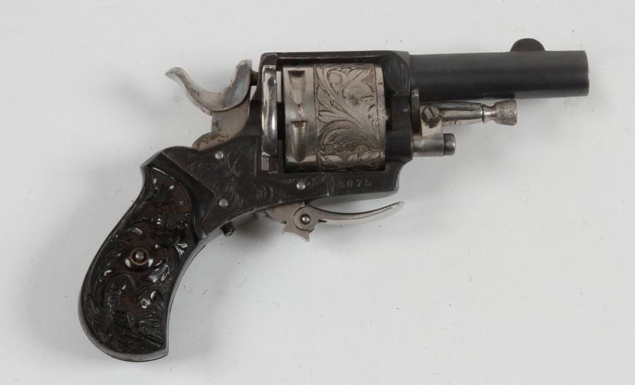 Revolver Bulldog, six coups, calibre 320.
Barillet et carcasse gravés de feuillages. Détente pliante. Plaquettes de crosse sculptées.
B.E. Vers 1880-1900. Finition bleuie. Dans un étui en cuir