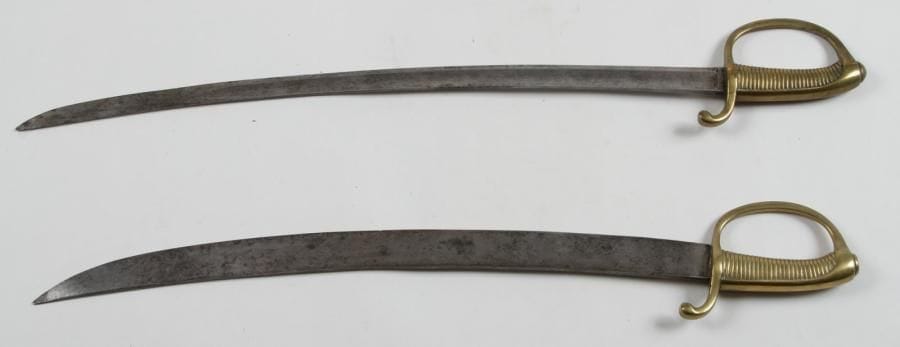 Deux sabres d'infanterie dit «Briquet», modèle allégé.
Monture en bronze. Lame à dos plat, contre-tranchant et pans creux.
B.E. SF. Vers 1830- 1850