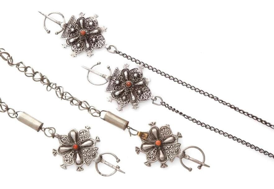 Deux paires de fibules en argent, Maroc, tribu du Haut Altas, Dadès, fin XIXe-début XXe siècle Fibules à décor de rosettes et cabochon central en corail avec leur chaîne. Long.: 75 cm et 67 cm PB.: 178 g et 171 g Two pairs of silver fibulae, Morocco, High Atlas, Dades, late 19th early 20th century