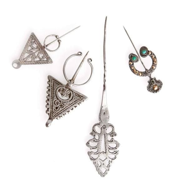 Quatre fibules en argent, Algérie et Maroc, XXe siècle Deux fibules triangulaires, l'une niellée et l'autre au poinçon du crabe, Algérie. La troisième en argent et cuivre, ornée de pierres turquoise. La dernière, longue, à décor de lobes ajourés avec poinçon simple. Long.: entre 6,5 et 7,5 cm; 14,5 cm PB.: Deux fibules: 19 g; fibule en argent et cuivre: 7 g; longue fibule: 8 g Four silver fibulae, Morocco, 20th century