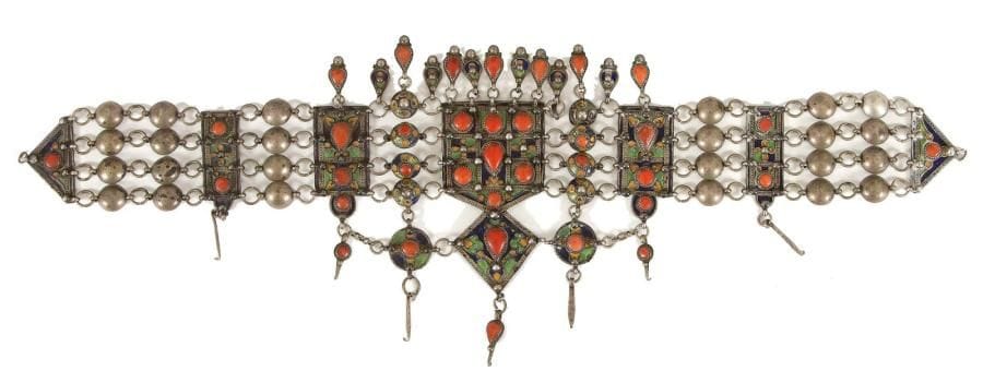 Parure de tête, en argent, Algérie, Grand Kabylie, Benni Yenni, XXe siècle Parure constituée de plaques en argent émaillées en polychromie et rehaussées de cabochons de corail. Elles sont reliées entre elles par quatre chaînes. Pendentifs centraux à pampilles également serties de corail. Dim.: long.: 56 cm; larg.: 19 cm P.: 402 g A silver head set, Morocco, 19th century