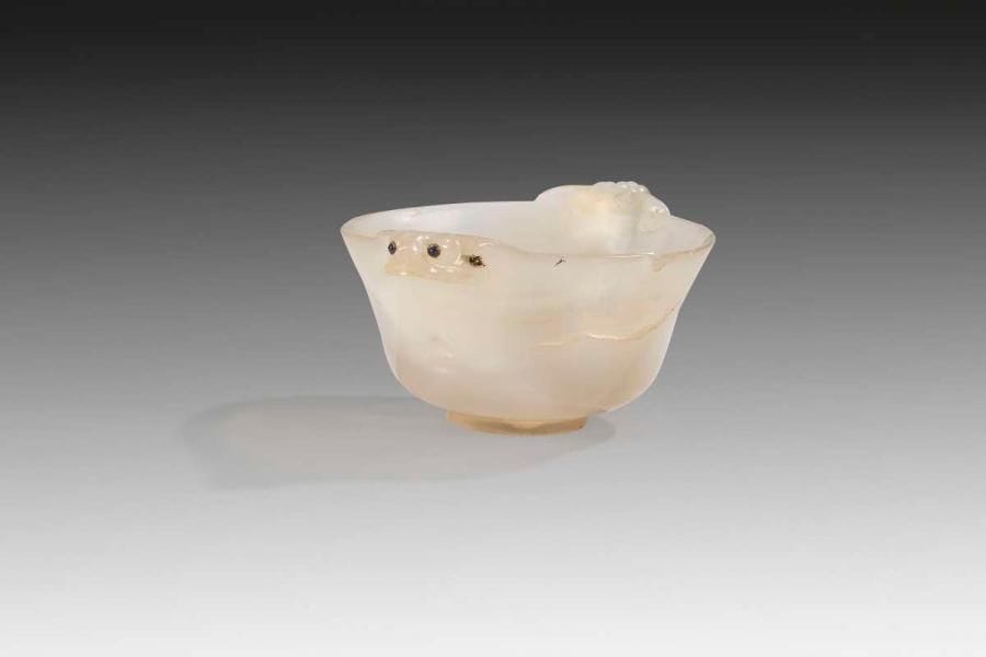Coupelle en jade blanc translucide, Iran safavide, XVIIe siècle Coupe évasée à prises de chimère et yeux en lapis cerclé d'or. Dim.: diam.: 7 cm; H.: 3,5 cm État: fêlure et accident au rebord et manque un oeil. Le jade est utilisé au XVIe siècle en Inde moghole pour réaliser des objets précieux comme des manches de dague, base de huqqa, des bols et des coupes. Il provient principalement des villes de Kashan et de Khotan et on lui prête de nombreuses vertus dont celle de prolonger la vie, l'immortalité. Voir Mulier-wiener Martina, catalogue exposition Von Istanbul bis Mogulinden, Francfort, 2008. A Safavid translucent jade cup, Iran, 17th century