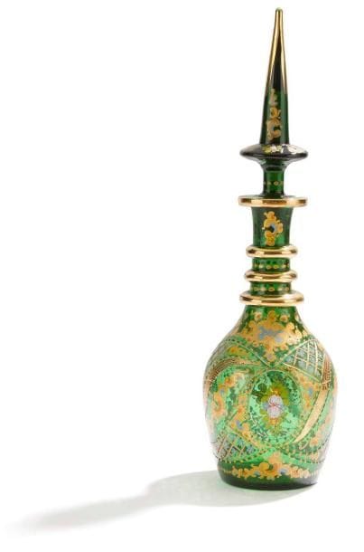 Carafe en verre incisé et doré, Bohème pour l'Iran, XIXe siècle Panse piriforme à col annelé sommée d'un bouchon conique, en verre transparent vert, à décor incisé et peint de fleurs polychromes et dorées. H.: 51,5 cm A Bohemian glass bottle and tapering stopper, 19th century