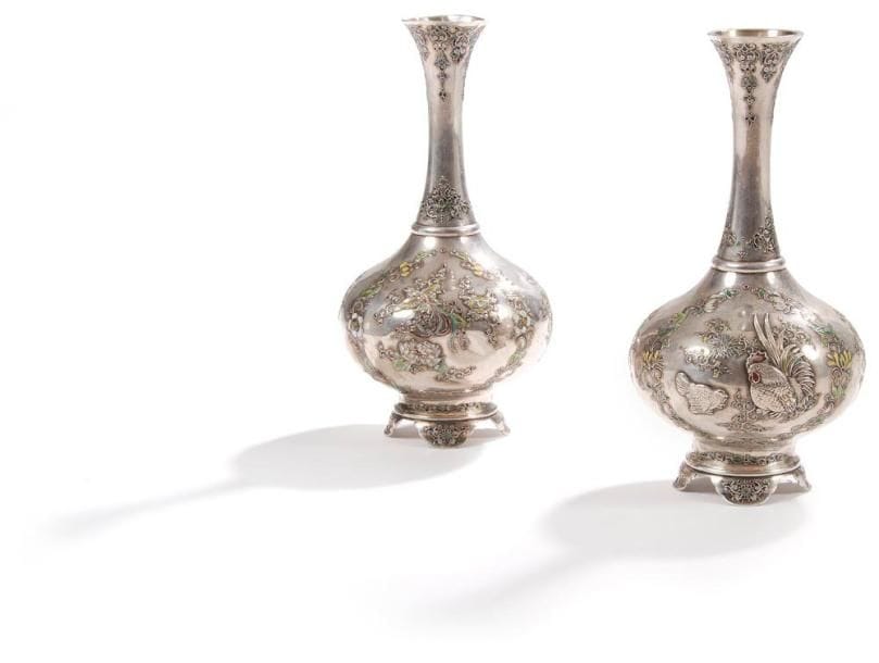 JAPON - Epoque MEIJI (1868 - 1912)
Paire de vases à panse basse en shibuichi décorés en émaux cloisonnés et en relief de coq, poule et phénix sur fond de fleurs et rinceaux. Au revers de la base la marque Hideaki dans une réserve rectangulaire. (Chocs).Haut.: 20 cm