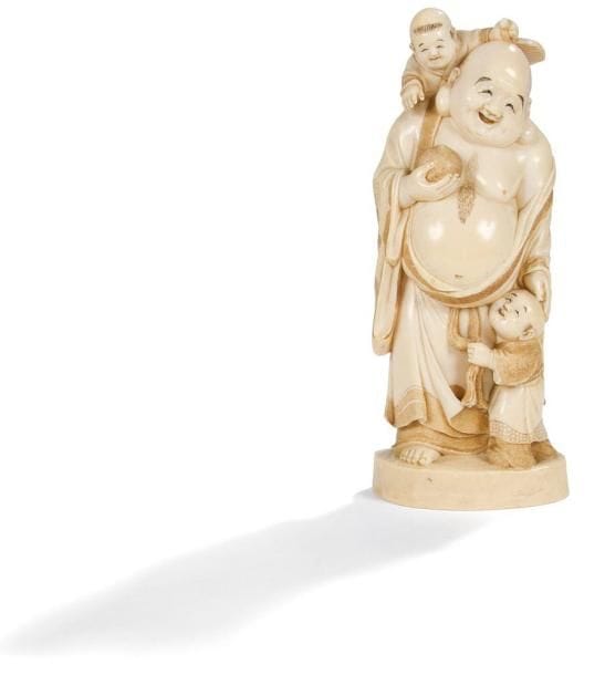 JAPON - Epoque EDO (1603 - 1868)
Okimono en ivoire à patine jaune représentant Hotei debout, un enfant sur le dos, un autre à ses pieds, tenant un tama. Signé dans un cartouche en laque rouge Muneharu. Haut.: 25 cm