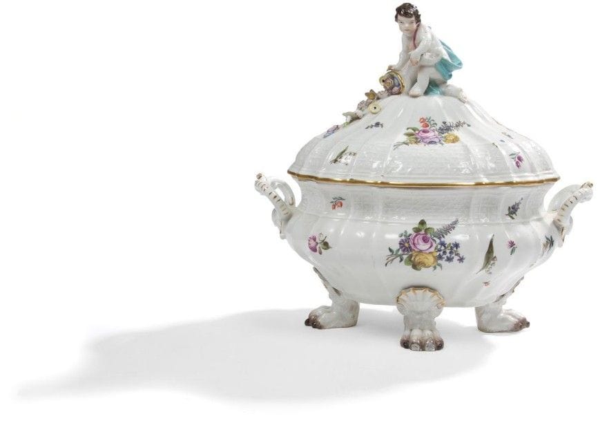 MEISSEN
Terrine ovale couverte en porcelaine à motifs de vannerie en léger relief sur les bords, décor polychrome de bouquets de fleurs, la prise du couvercle formée d'un enfant drapé tenant une corne d'abondance remplie de fleurs, la terrine repose sur quatre pattes de lion et coquille Marquée: épées croisées en bleu XVIIIe siècle, vers 1745 Longueur: 32 cm. Éclats à l'extrémité des pieds et aux fleurs sur le couvercle