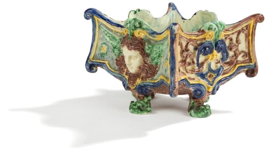 Ecole de Paris
Jardinière carrée reposant sur quatre pieds à décor polychrome et en relief de masques ailés et motifs de cuir découpés cernés de rinceaux Fin du XIXe siècle.. Longueur: 19 cm. Un angle restauré