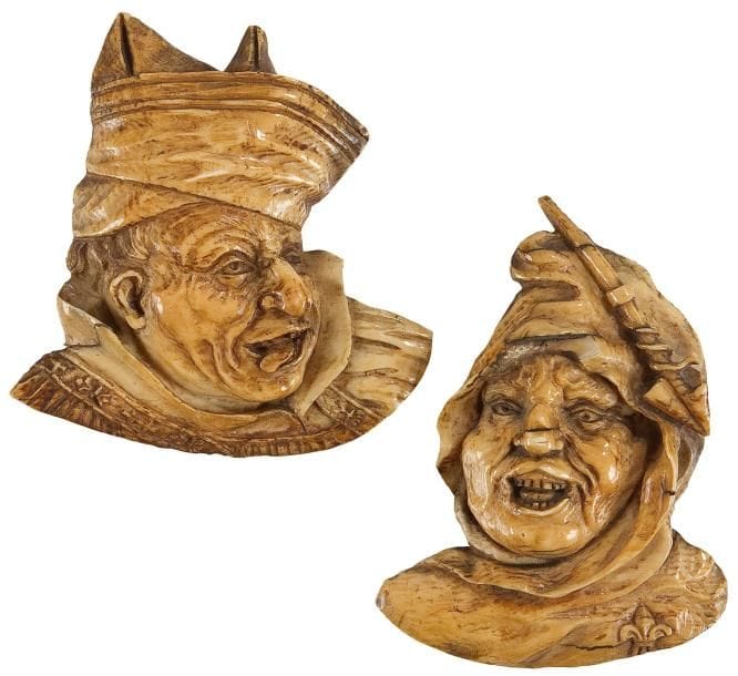 Paire de bustes en ivoire sculpté en applique de personnages grotesques, l'un grimaçant et tirant la lange coiffé d'un chapeau à deux cornes et l'autre portant un bonnet avec une flèche accrochée, une fleur de lys sur l'épaule Allemagne, XIXe siècle. Hauteurs: 8 et 8,7 cm. Soclée. (petit manque à l'un sur le bas du bonnet)