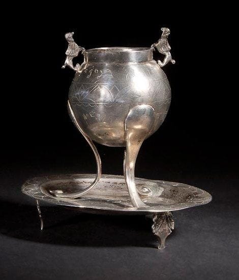 BOÎTE À AROMATES Europe, probablement Allemagne, XVIIIe siècle. Argent gravé et moulé. Poinçons sur le bord supérieur et sous l'assiette. Hauteur: 12,5 cm Poids: 241,5 g
Compartiment à aromates sphérique, décoré d'une frise et reposant sur trois pieds courbes. Les pieds sont rivetés à une assiette ronde reposant sur trois petits pieds en forme de feuilles. Deux lions se font face à la bouche du compartiment. Inscrit en hébreu sur le compartiment:[Sois fort et béni] suivi par la fin de la bénédiction sur les épices et de la date en hébreu 5460 correspondant à l'année 1700 ainsi que deux mains de prêtre sous une couronne qui indiquent peut-être que le propriétaire était un Cohen. Mots-clés: Judaica, Jewish, Hebrew, Judaïsme, Hébreu.
Spice Box. Europe, probably German, 18th century. Cast/engraved silver. Hallmarks on the top and underneath the dish.