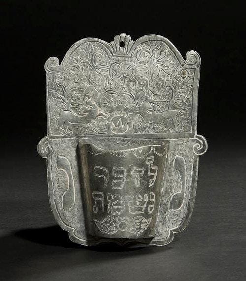 [YAHRZEIT] LAMPE MéMORIALE Allemagne, XVIIIe siècle. Étain gravé. Hauteur: 15,5 cm
Coupe conique coupée en deux et soudée à une plaque. La plaque est gravée d'une couronne supportée par deux animaux unicornes et d'un décor de fleurs et de feuillage. De chaque côté de la demi-coupe est gravée une lettre en hébreu. Les deux lettres forment ensemble l'abréviation de l'expression: Lumière de l'âme La demi-coupe est gravée de l'inscription hébraïque: En mémoire de Mots-clés: Judaica, Jewish, Hebrew, Judaïsme, Hébreu.
Yahrzeit Memorial Lamp. Southern Germany, 18th century. Engraved pewter.